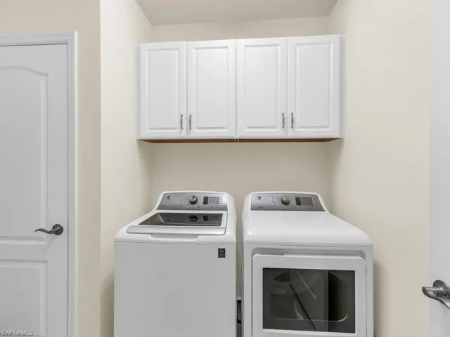 Clothes washing area featuring separate washer and dryer and cabinets