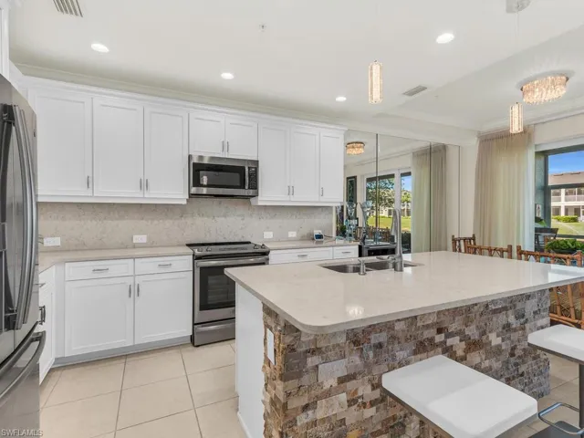 Kitchen with a kitchen breakfast bar, a healthy amount of sunlight, hanging light fixtures, and stainless steel appliances