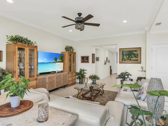 Living room with ceiling fan, ornamental molding, and light tile patterned floors