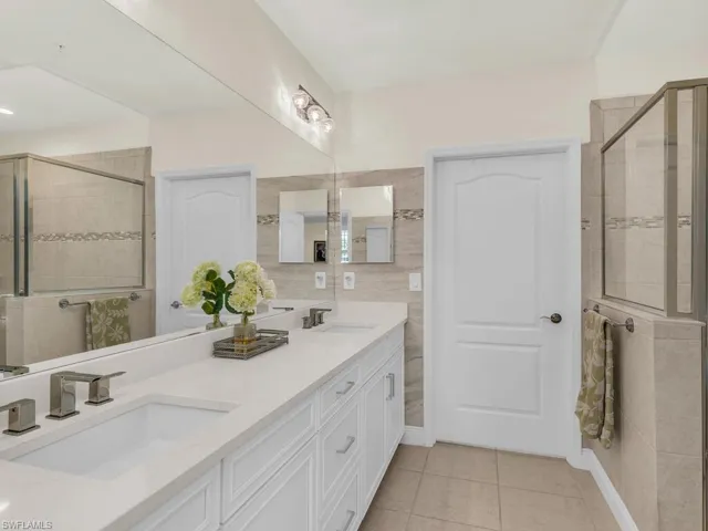 Bathroom with tile patterned flooring, vanity, and an enclosed shower