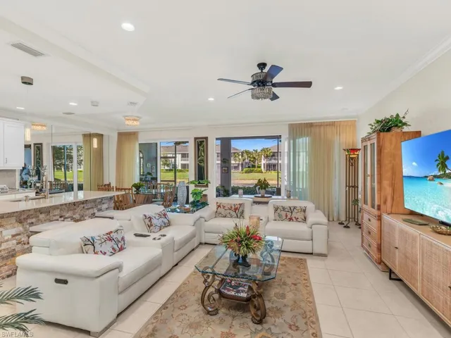Living room with ceiling fan, a healthy amount of sunlight, light tile patterned floors, and crown molding
