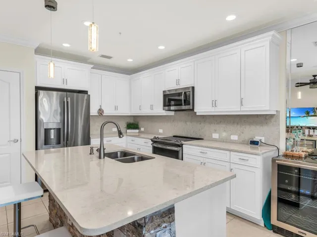 Kitchen with sink, stainless steel appliances, wine cooler, a breakfast bar area, and a center island with sink