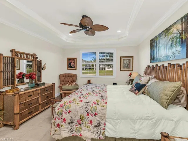 Bedroom featuring a tray ceiling, ceiling fan, light tile patterned flooring, and ornamental molding