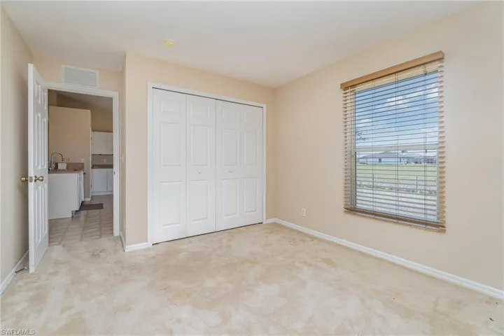 bedroom with light colored carpet, baseboards, a sink, and a closet