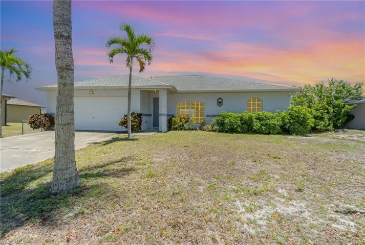 Ranch-style house with an attached garage, stucco siding, driveway, and a front yard