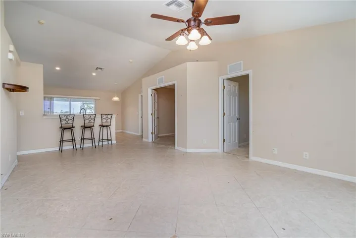 living room featuring a ceiling fan, lofted ceiling, light tile patterned floors, and baseboards