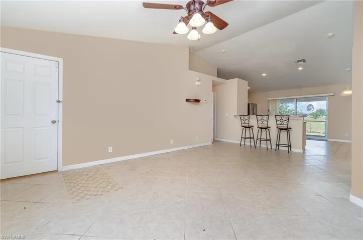 living room with ceiling fan, light tile patterned floors, baseboards, and vaulted ceiling