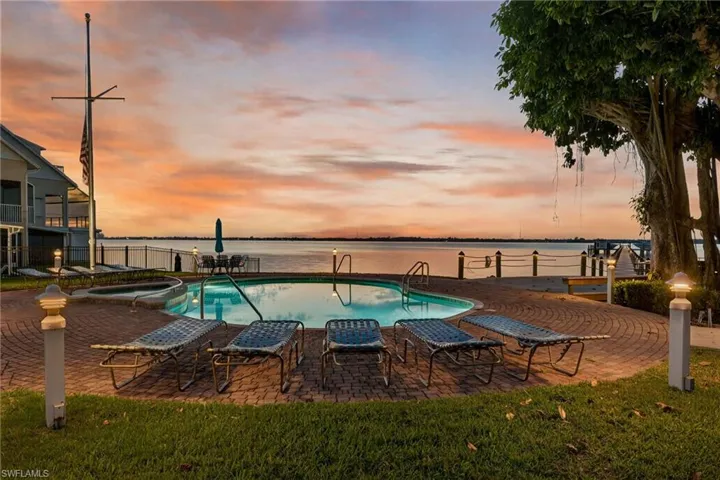 View of pool featuring a water view, a patio, and a pool with connected hot tub