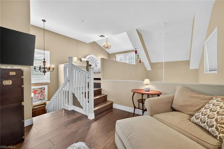 Living room with vaulted ceiling, dark wood finished floors, a chandelier, and stairs
