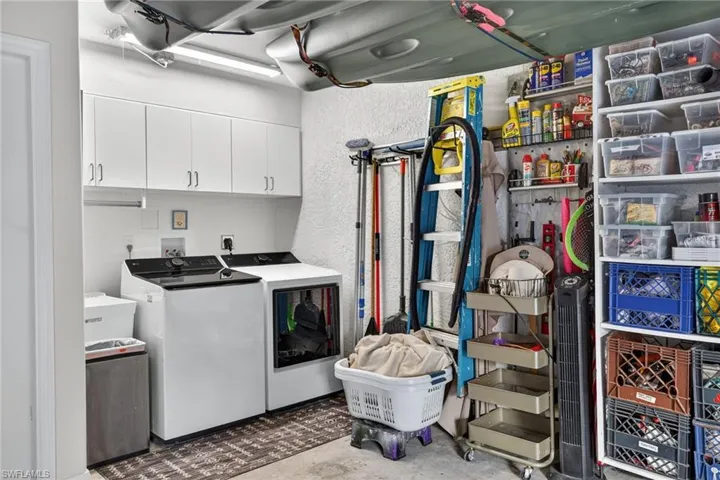 Laundry room with cabinet space, washer and dryer, concrete flooring, and a textured wall