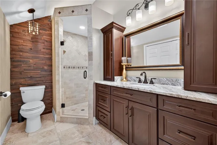 Full bathroom with vanity, a stall shower, and lofted ceiling