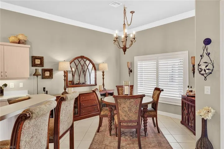 Dining area featuring light tile patterned floors, ornamental molding, and a chandelier