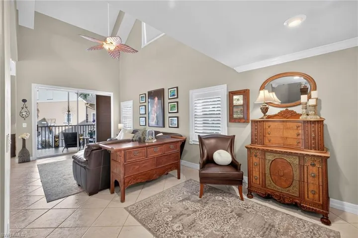 Living room with plenty of natural light, light tile patterned floors, ceiling fan, and high vaulted ceiling