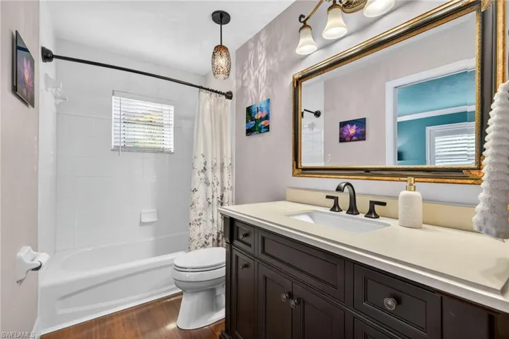 Bathroom featuring dark wood finished floors, shower / bath combo, and vanity