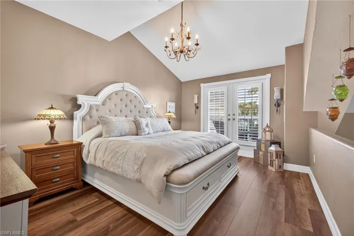 Bedroom featuring vaulted ceiling, french doors, dark wood-style floors, access to exterior, and a chandelier Loft