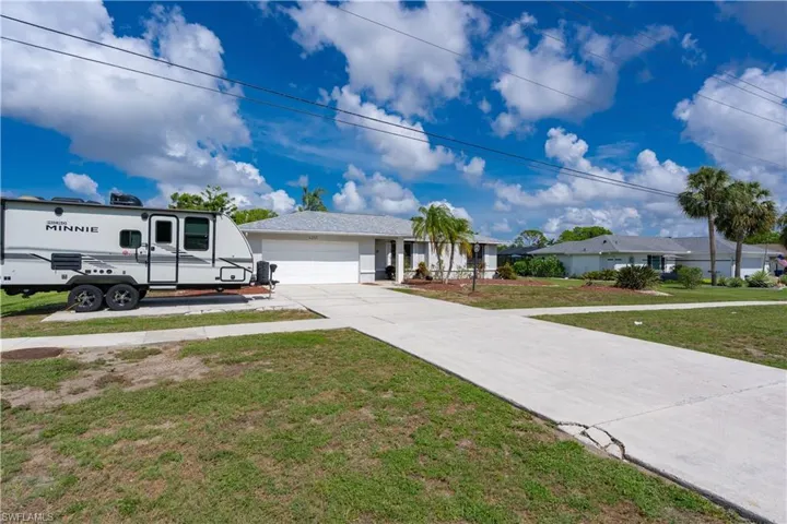 View of front of property with a garage, a front yard, driveway, and stucco siding