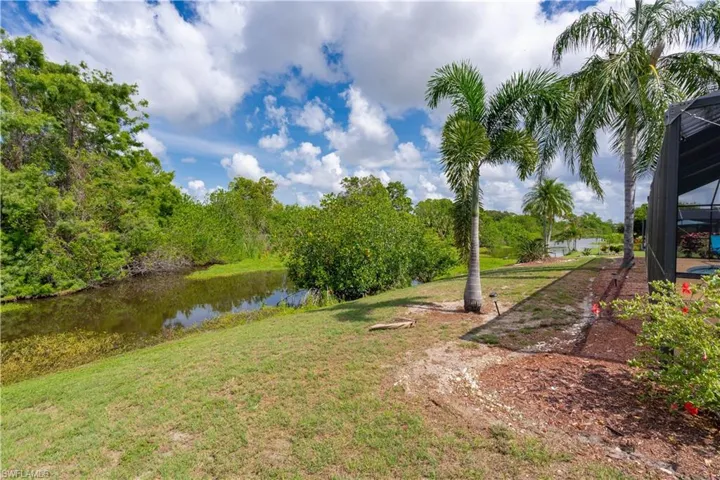 View of green lawn with a water view and a lanai
