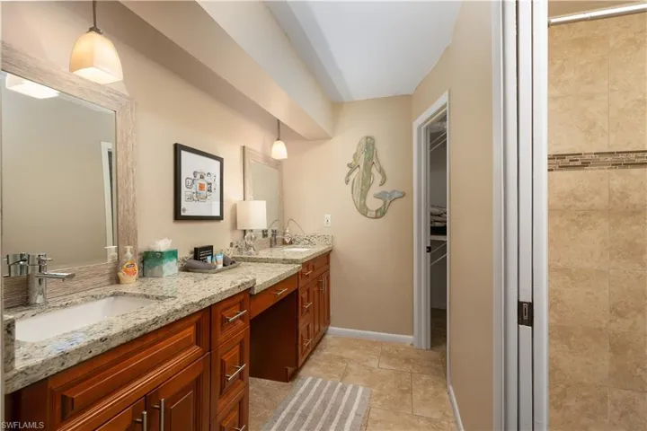 Bathroom with double vanity, a spacious closet, and tile patterned flooring