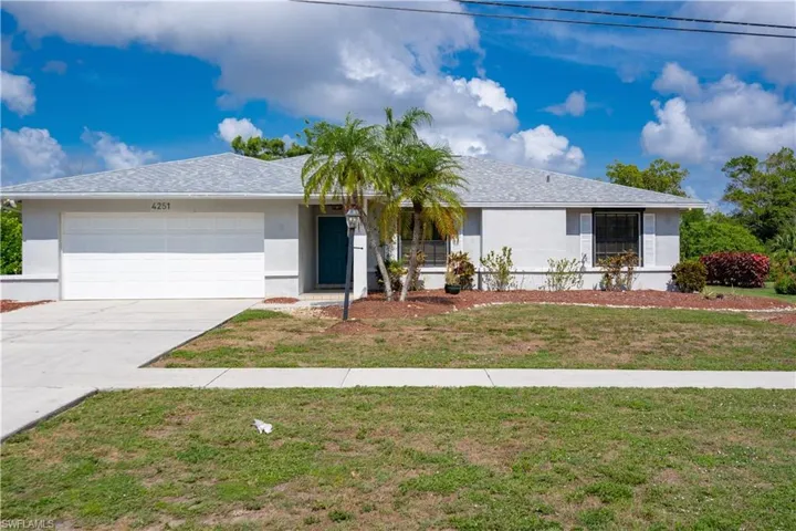Single story home featuring a garage, stucco siding, driveway, and a front yard