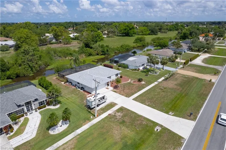 Aerial perspective of suburban area featuring a nearby body of water and a tree filled landscape
