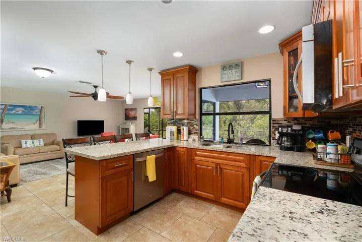 Kitchen with stainless steel dishwasher, a sink, backsplash, a peninsula, and a breakfast bar area