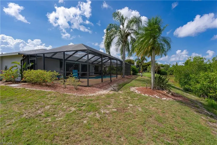 View of green lawn with an outdoor pool and a lanai