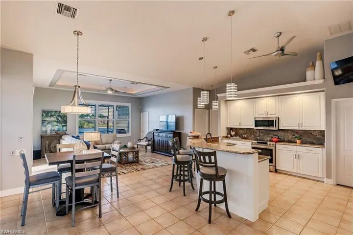 Kitchen with a ceiling fan, pendant lighting, a breakfast bar, appliances with stainless steel finishes, and open floor plan