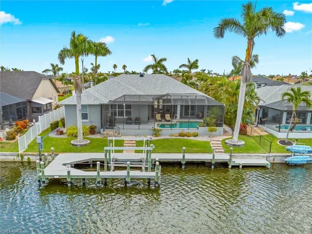 Rear view of house with a sunroom, boat lift, and a water view