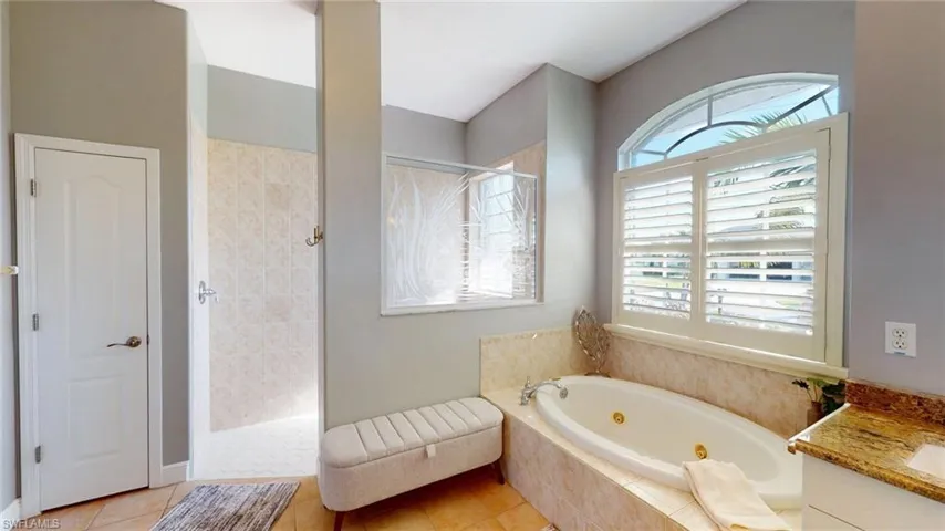 Full bathroom with a tub with jets, walk in shower, vanity, and light tile patterned floors