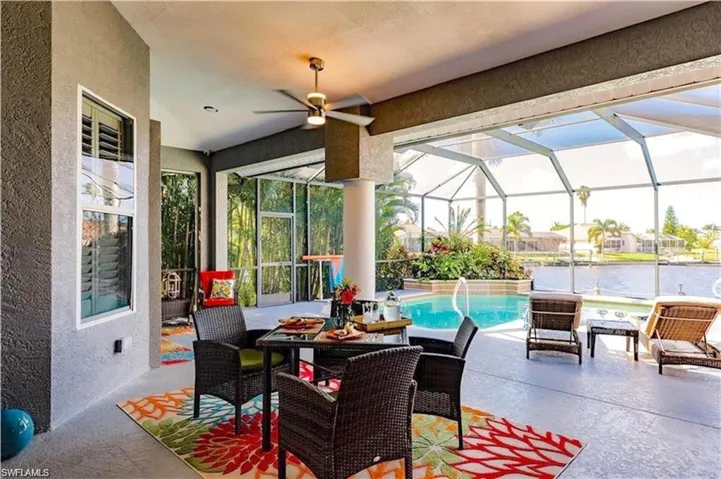 View of patio / terrace with glass enclosure, an outdoor pool, a water view, a ceiling fan.