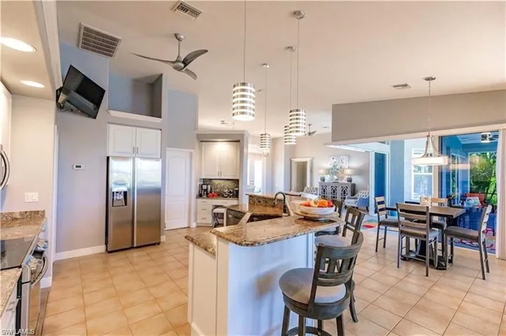 Kitchen with appliances with stainless steel finishes, a breakfast bar area, decorative light fixtures, and light stone countertops