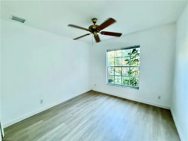 Unfurnished room featuring wood finished floors, baseboards, and ceiling fan