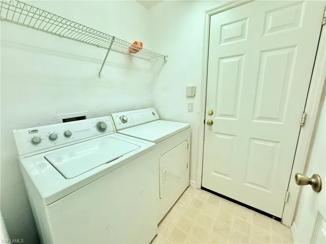 Washroom with washing machine and clothes dryer, baseboards, and light floors