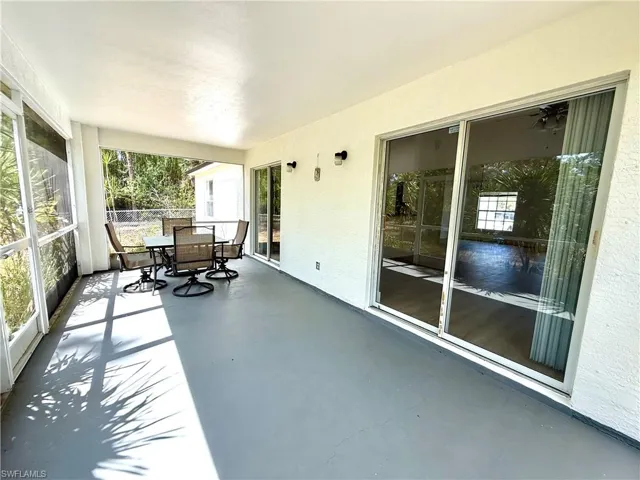 Unfurnished sunroom featuring finished concrete floors, outdoor dining area, and a textured wall