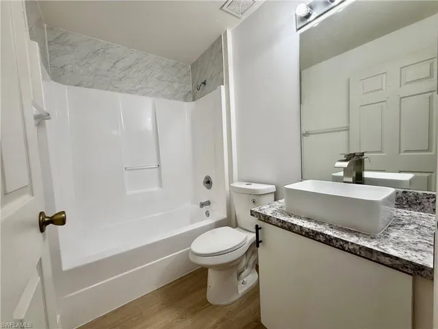 Bathroom featuring wood finished floors, vanity, toilet, and shower / bathtub combination