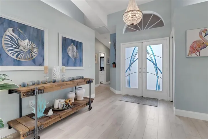 Entrance foyer with a chandelier, french doors, light wood-style flooring, and lofted ceiling
