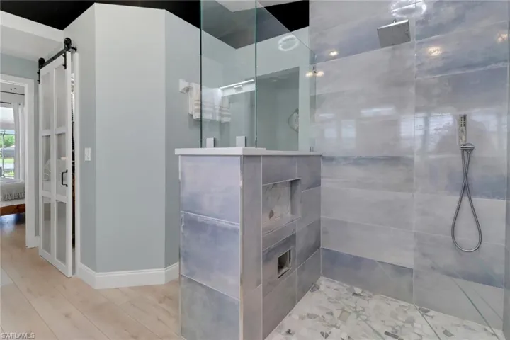 Full bath with tiled shower and light wood-style flooring