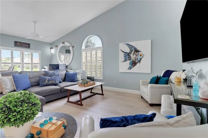 Living area featuring high vaulted ceiling, wood finished floors, and ceiling fan