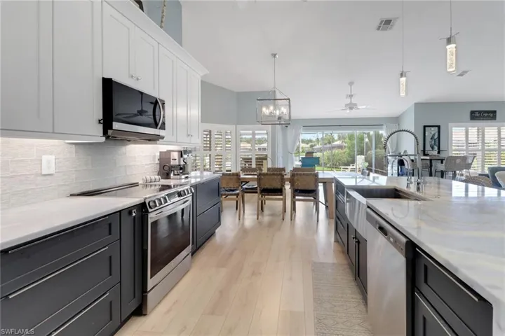 Kitchen with decorative light fixtures, ceiling fan, white cabinetry, stainless steel appliances, and dark cabinets