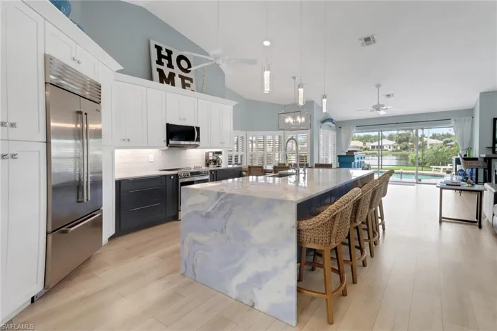 Kitchen featuring pendant lighting, white cabinets, light stone countertops, appliances with stainless steel finishes, and open floor plan