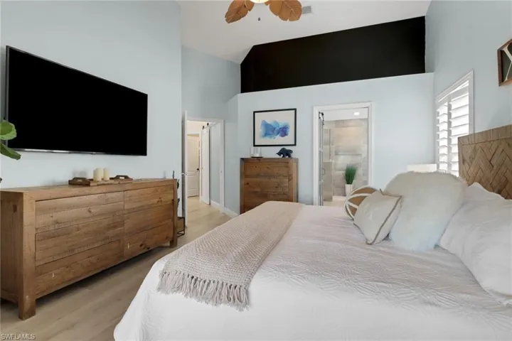 Bedroom with a ceiling fan, light wood-type flooring, ensuite bath, and lofted ceiling