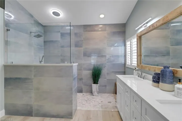 Full bathroom featuring double vanity, a walk in shower, and recessed lighting