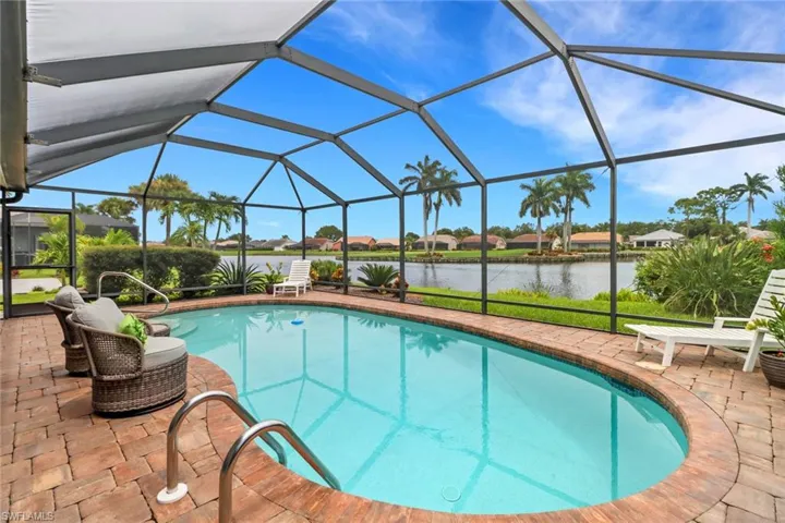 Outdoor pool featuring glass enclosure, a water view, a sunroom, and a patio