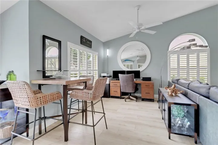 Office with light wood-style floors, lofted ceiling, and ceiling fan