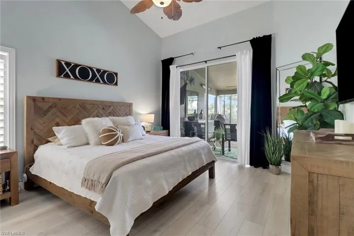 Bedroom with lofted ceiling, light wood finished floors, access to outside, and ceiling fan
