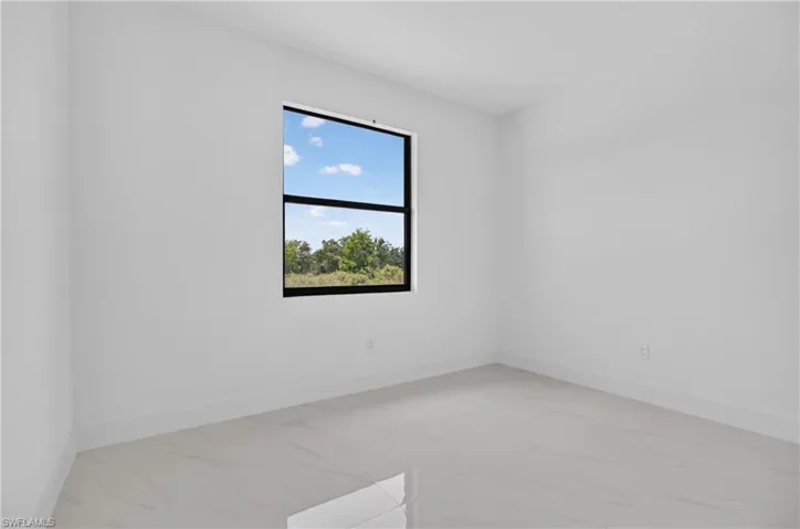 Bright interior space featuring a large window with black framing, offering exterior scenery