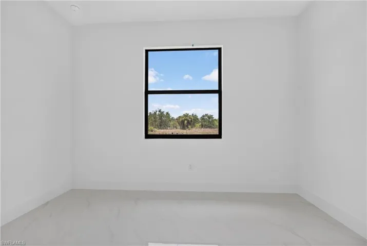 Minimalist room featuring a large black-framed window, recessed ceiling lighting, and light-toned tile flooring