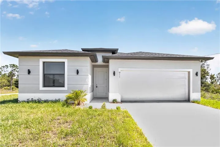 Modern stucco exterior featuring a white garage door, dark framed windows, and exterior wall sconces