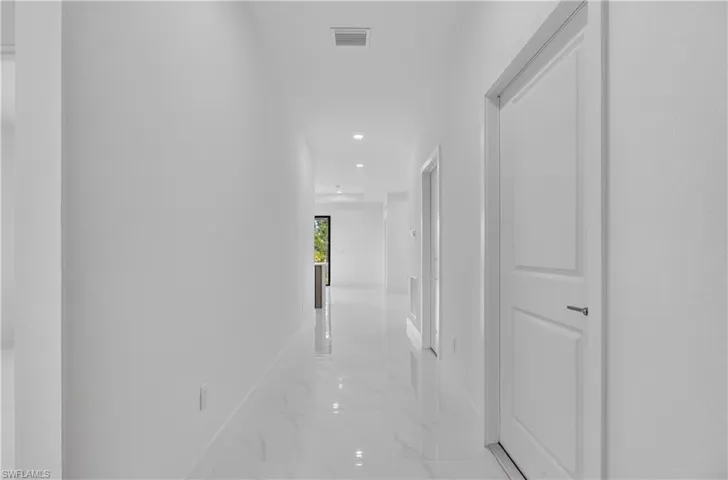 Hallway featuring recessed lighting, white walls, white doors, and polished tile flooring