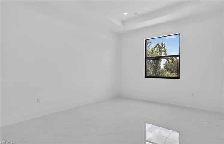 Neutral interior featuring a black-framed window, recessed lighting, a tray ceiling, light-toned walls, and wood-finish flooring